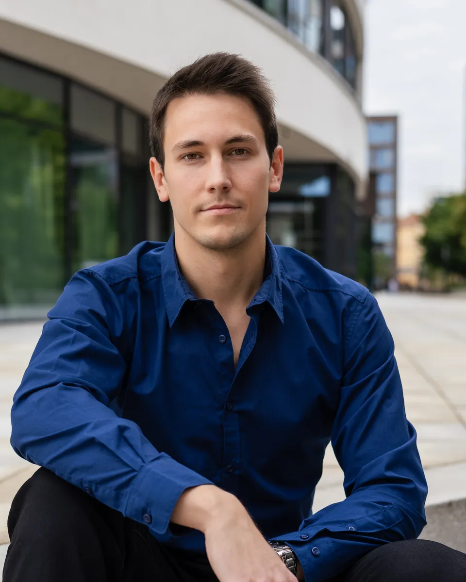 Lukáš Gurecký sitzt auf Stufen vor einem modernen Gebäude